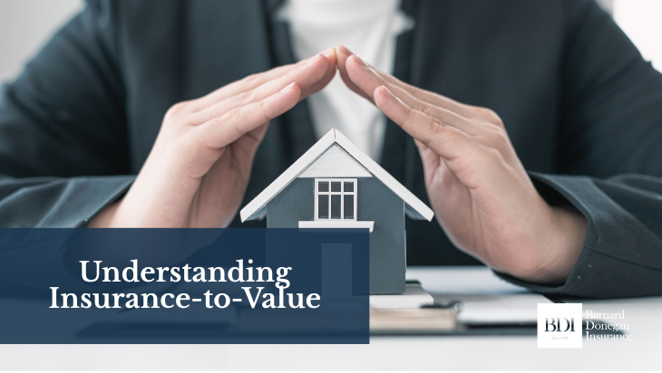 Hands forming a protective roof over a miniature house model on a desk, symbolizing property insurance coverage.