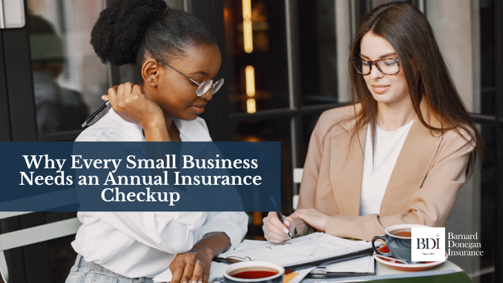 Two businesswomen reviewing paperwork and discussing documents at a café table with coffee mugs.